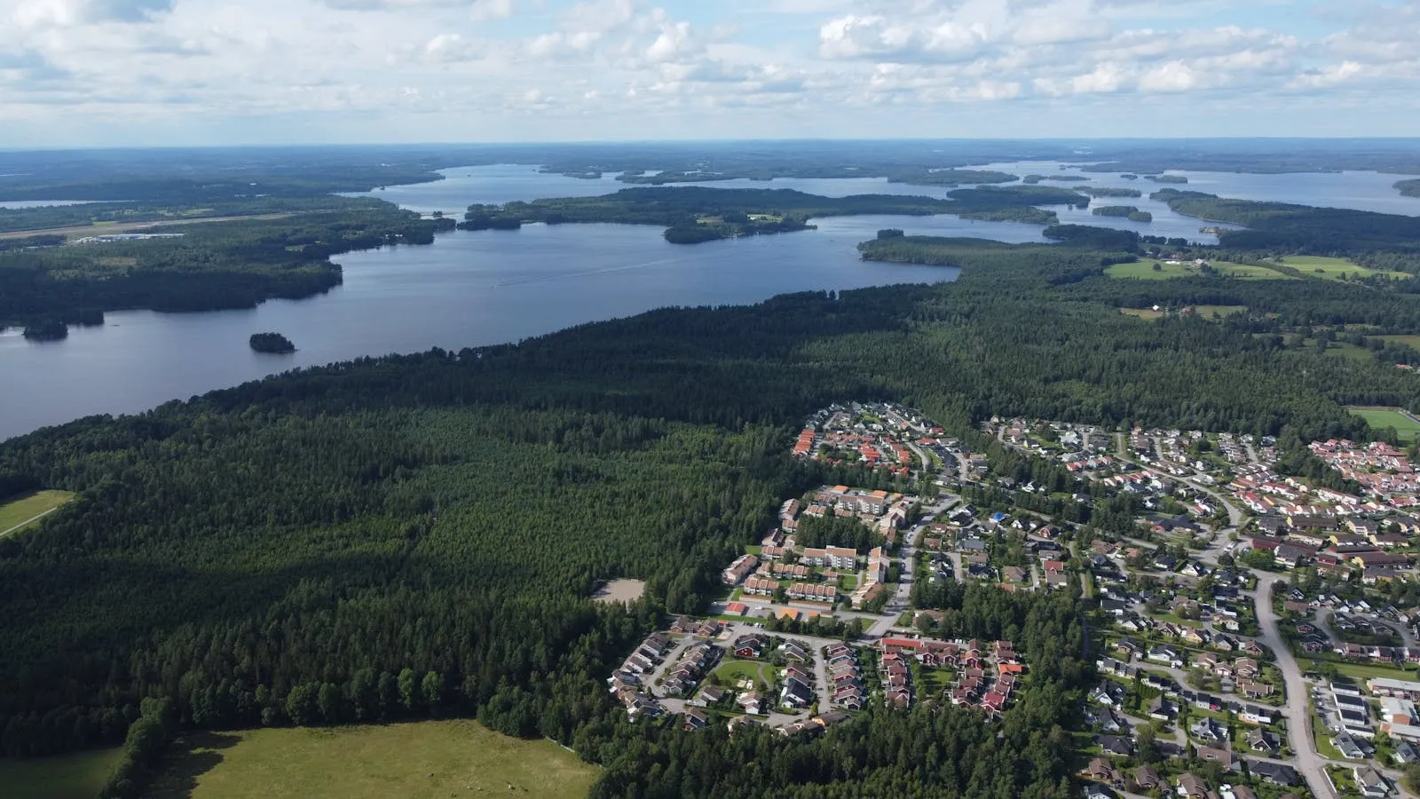 Panoramic view of a Swedish lake surrounded by forest under summer sky