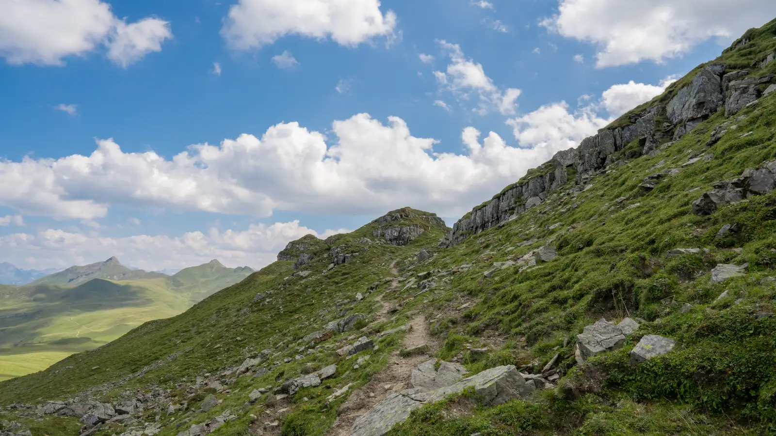 Hikers on an alpine trail with panoramic Swiss Alps behind