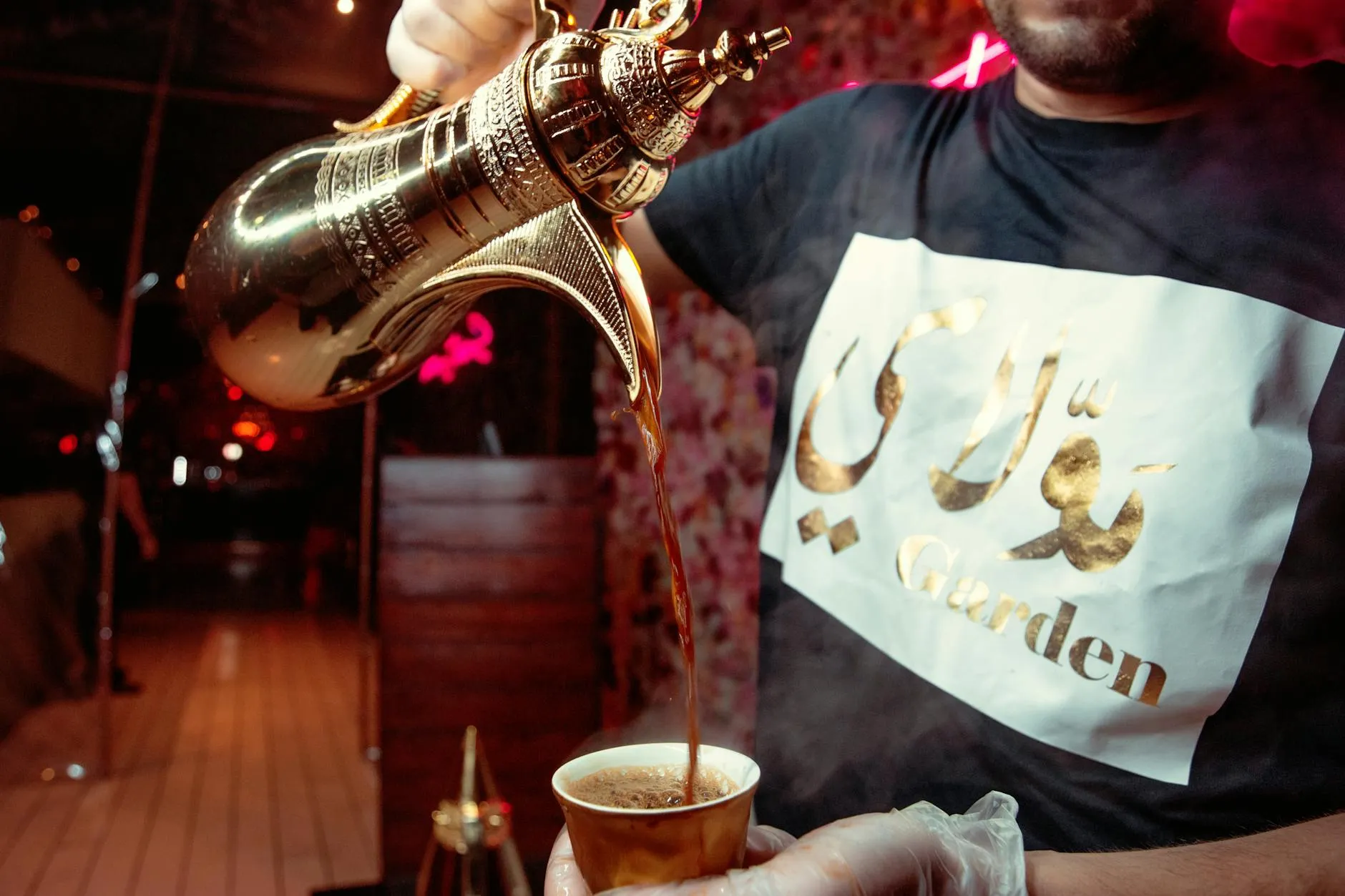 Traditional Arabic coffee being poured from a dallah into a finjan cup