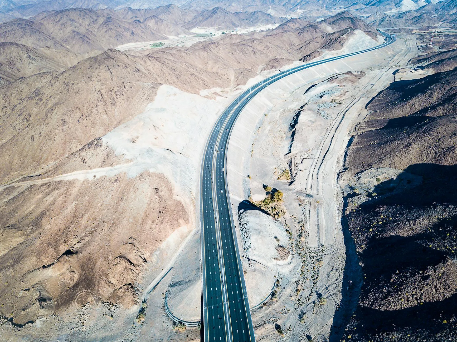Winding mountain road through Hajar range with desert valleys below
