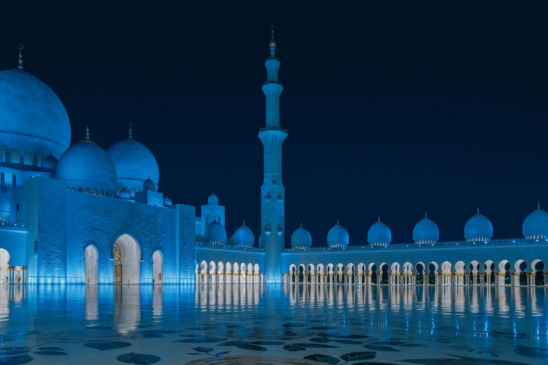 Sheikh Zayed Grand Mosque illuminated at night with reflection in water