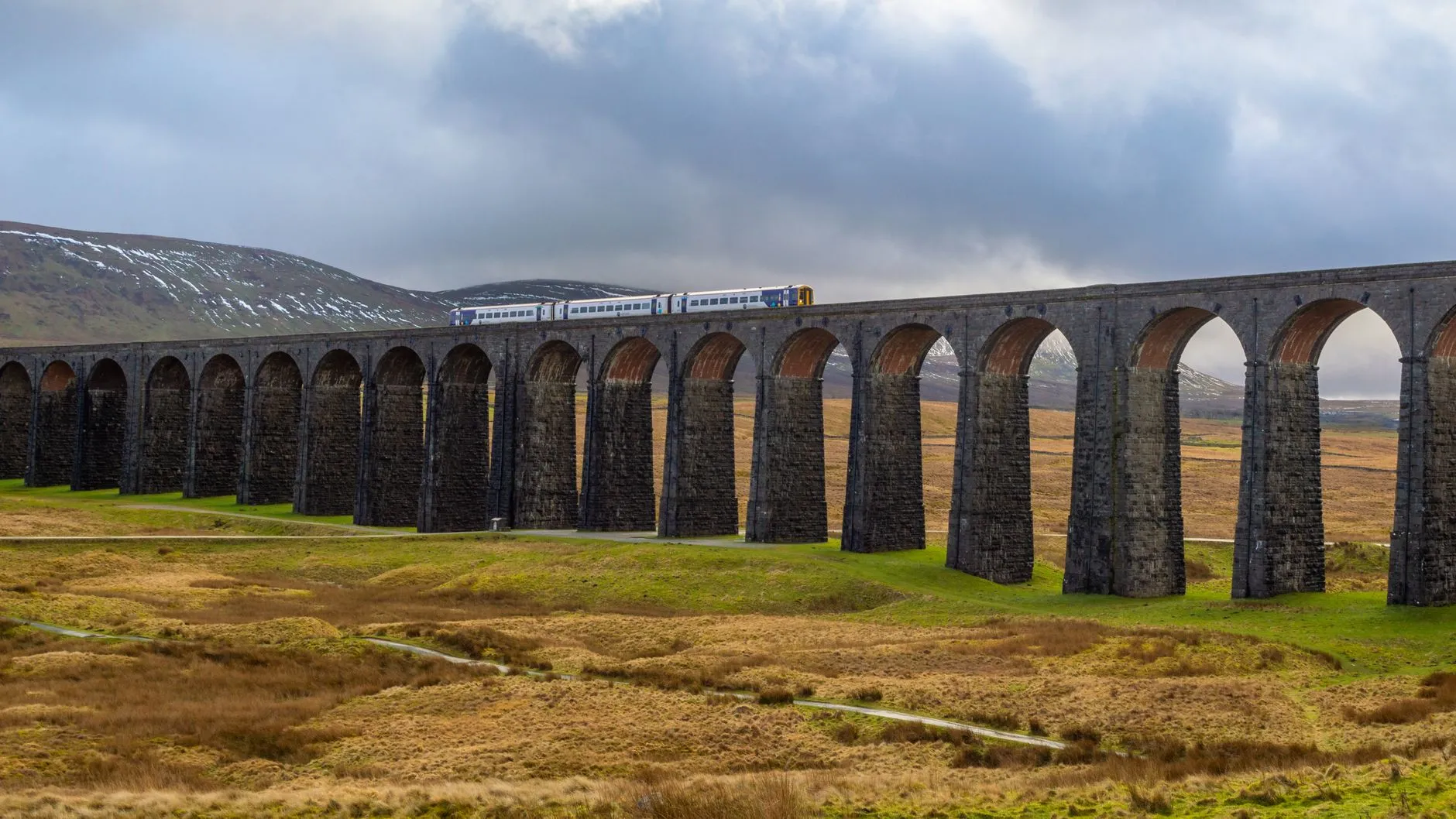 Train crossing a stone viaduct through green English countryside