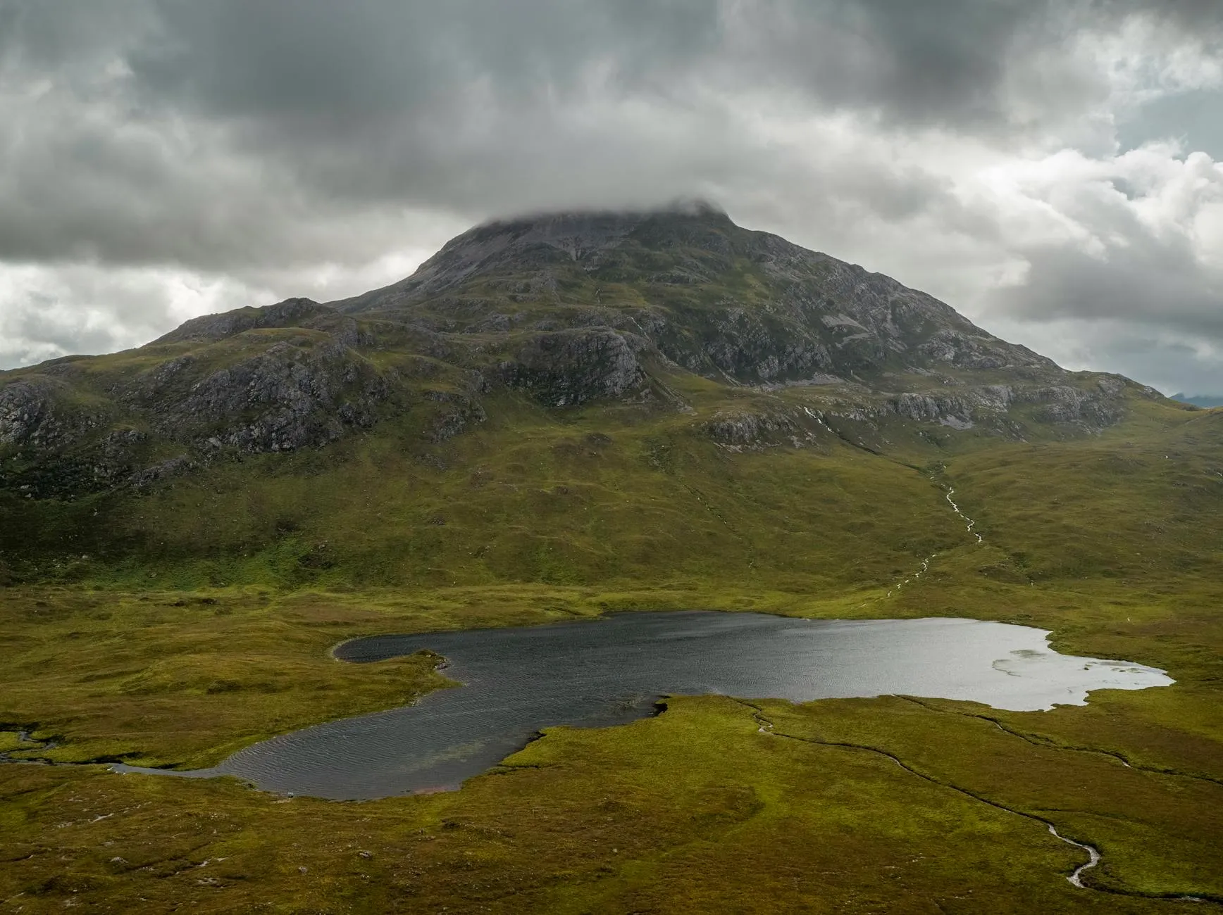 Scottish loch surrounded by mountains under dramatic skies