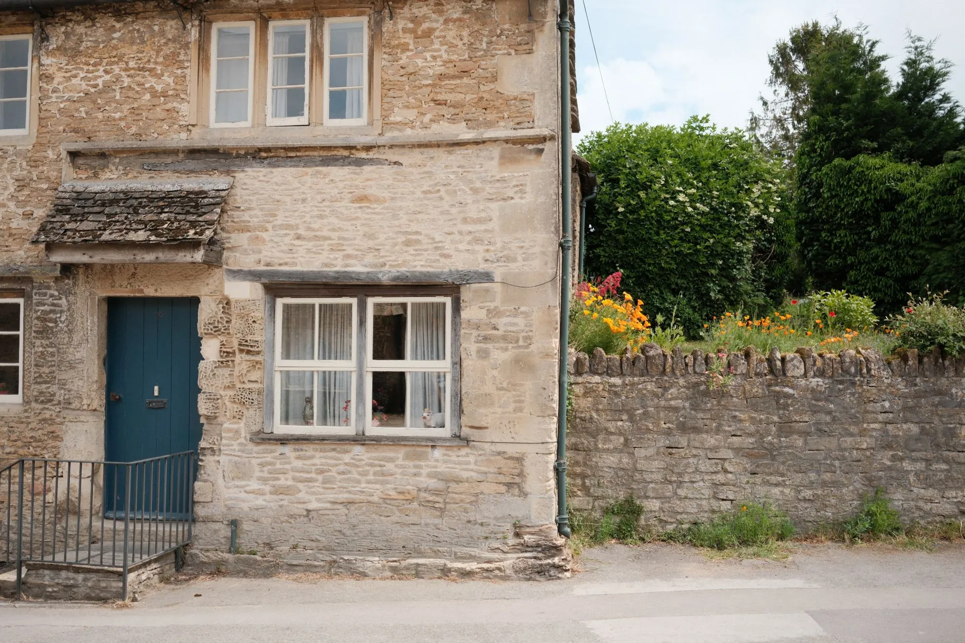 Honey-stone cottages in a Cotswolds village with flowers