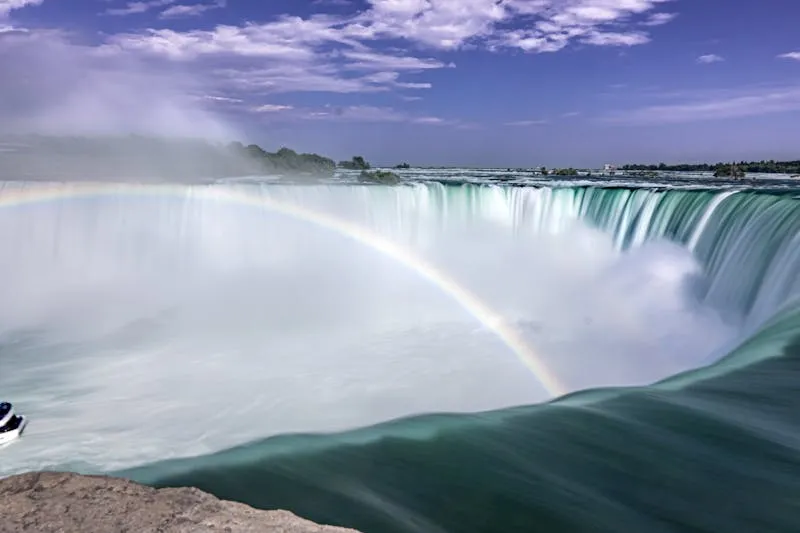 Niagara Falls with mist and rainbow rising from the cascade