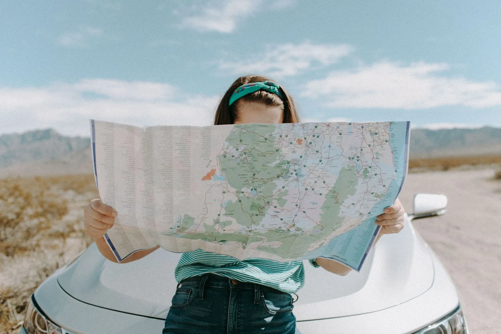 Traveller checking a road map beside a rental car