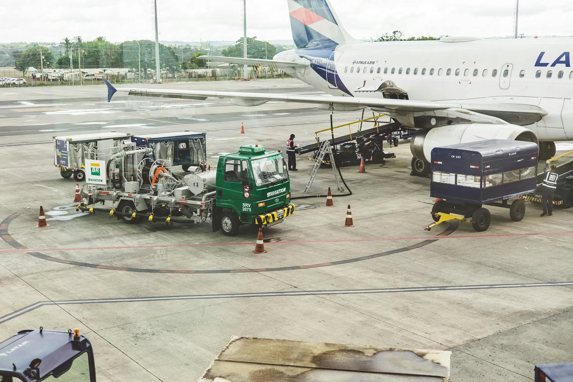 Ground support services in action at an airport terminal with visible aircraft and service vehicles.